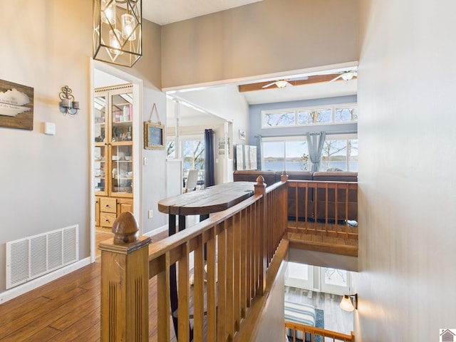 interior space featuring a ceiling fan, visible vents, baseboards, and wood finished floors