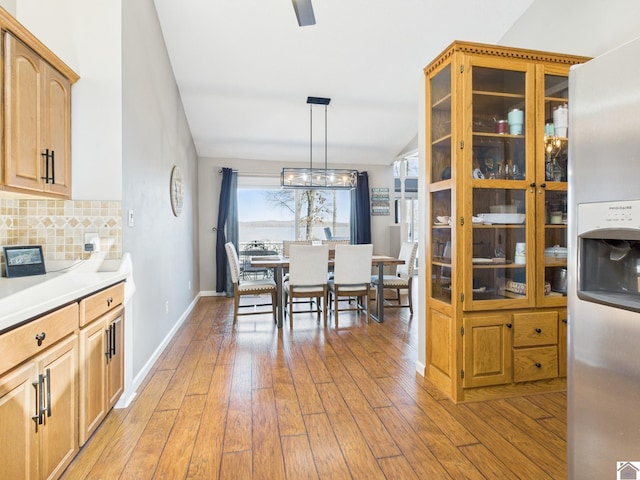 dining space featuring vaulted ceiling, ceiling fan, light wood-type flooring, and baseboards