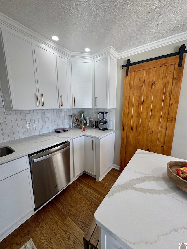 kitchen featuring a barn door, tasteful backsplash, white cabinets, dark wood-style flooring, and stainless steel dishwasher