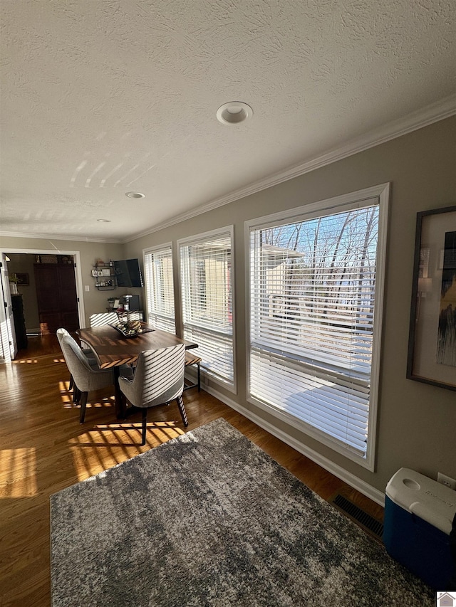 dining area with a wealth of natural light, visible vents, dark wood-type flooring, and ornamental molding