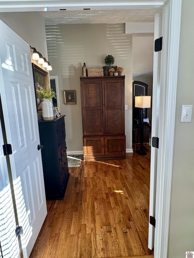 corridor featuring baseboards and wood finished floors