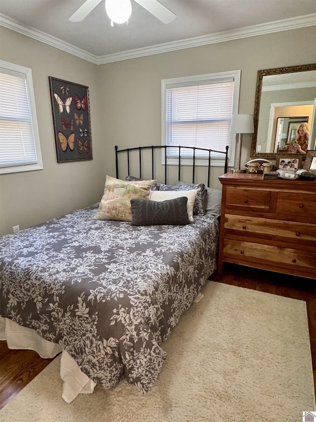 bedroom with wood finished floors, a ceiling fan, and crown molding