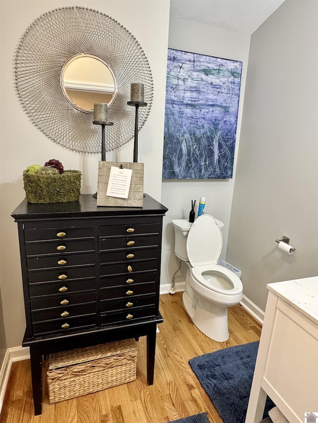 bathroom featuring vanity, wood finished floors, toilet, and baseboards