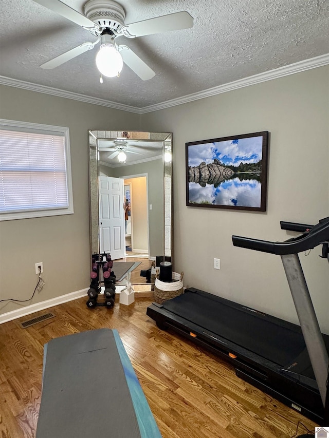 workout area with baseboards, visible vents, ornamental molding, wood finished floors, and a textured ceiling