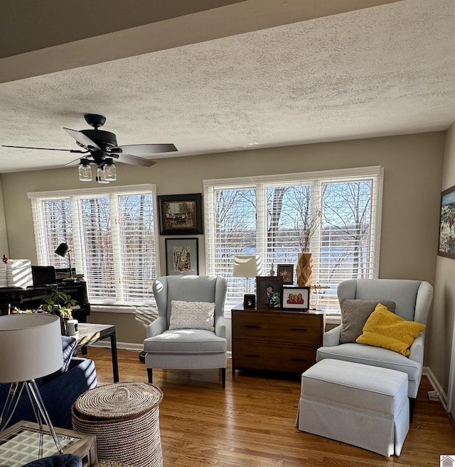 living area featuring a wealth of natural light, ceiling fan, a textured ceiling, and wood finished floors