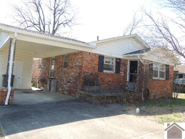 view of front of home with a carport, brick siding, and driveway