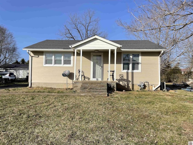 bungalow-style home with a shingled roof, a front yard, and central AC