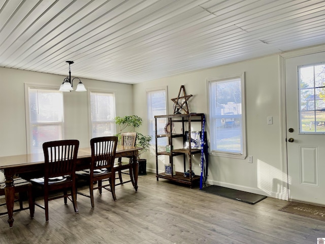 dining area with light wood-style floors, baseboards, and an inviting chandelier