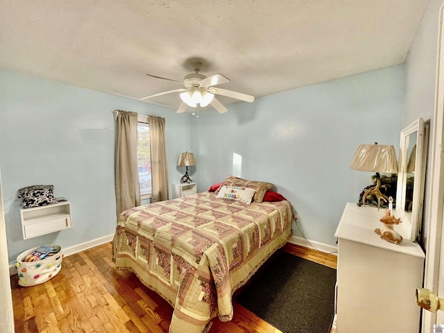 bedroom with ceiling fan, a textured ceiling, baseboards, and wood finished floors