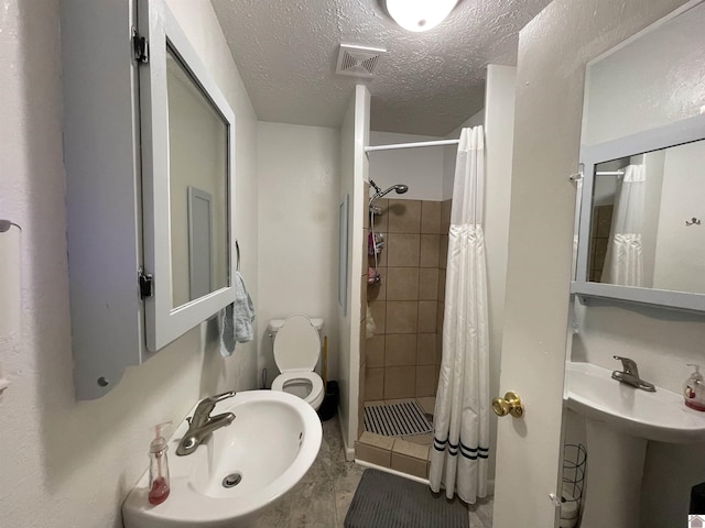 bathroom with a textured ceiling, a sink, visible vents, and a shower stall