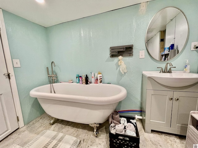 full bathroom with a freestanding bath, a textured wall, and vanity