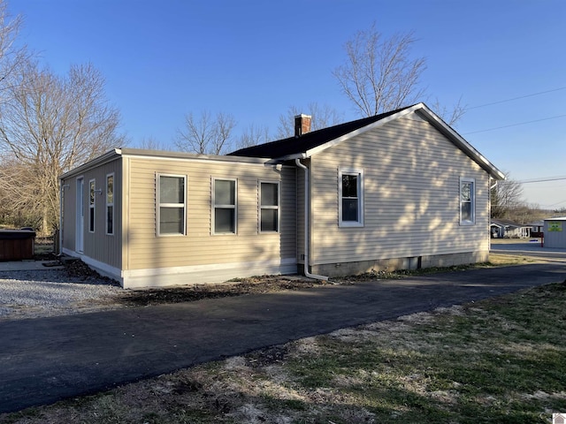 view of property exterior with driveway and a chimney