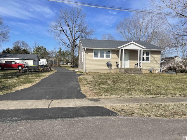 bungalow-style home featuring driveway, roof with shingles, and a front yard