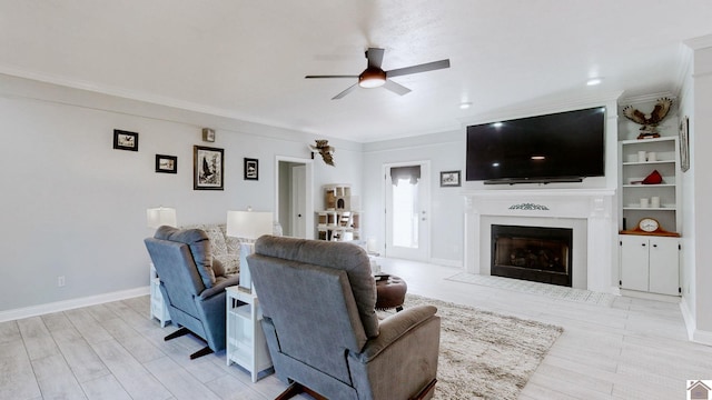living area featuring crown molding, a fireplace with flush hearth, baseboards, and ceiling fan
