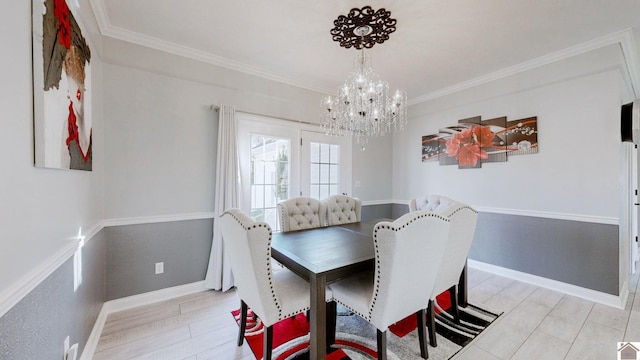 dining space with baseboards, an inviting chandelier, ornamental molding, and light wood finished floors