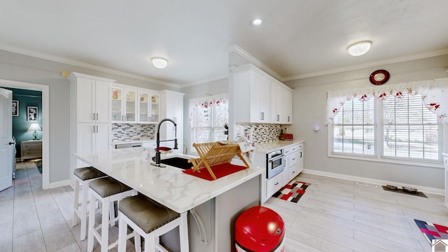 kitchen with decorative backsplash, crown molding, white cabinets, and oven