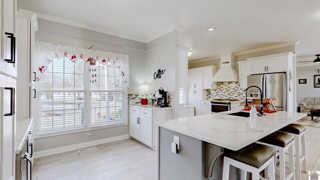 kitchen featuring visible vents, stainless steel fridge with ice dispenser, a sink, custom range hood, and range with gas cooktop