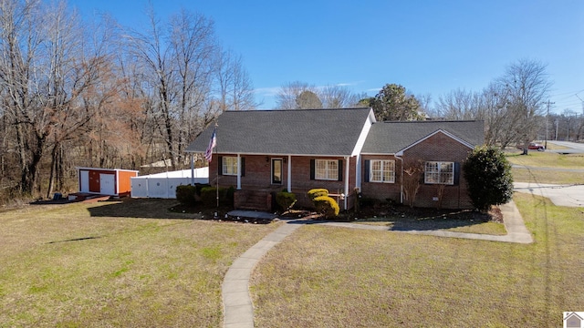 view of front of house featuring a front yard, fence, brick siding, and roof with shingles