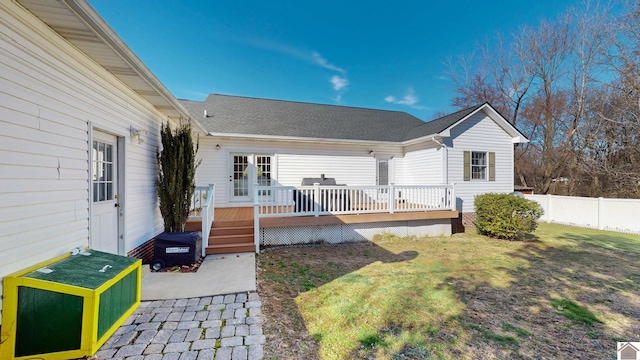 rear view of house featuring a deck, a shingled roof, a yard, and fence