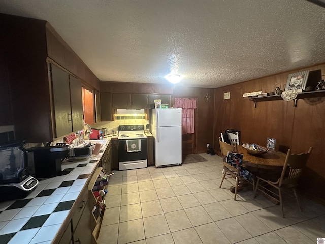 kitchen featuring light tile patterned flooring, freestanding refrigerator, range with electric cooktop, tile counters, and under cabinet range hood