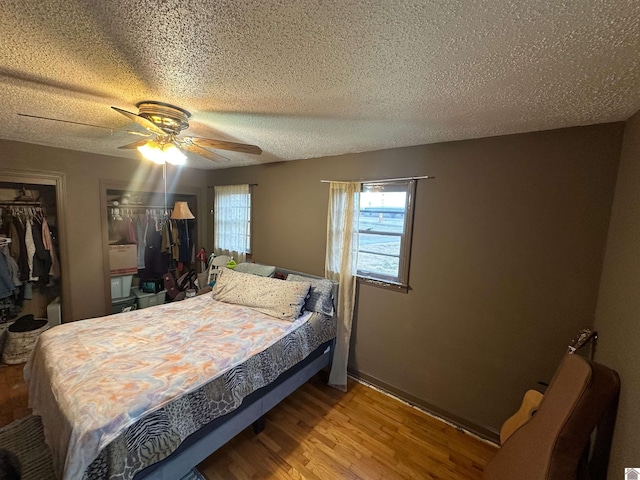 bedroom with a textured ceiling, wood finished floors, a closet, and ceiling fan