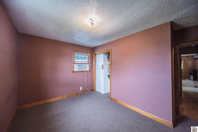 carpeted spare room with cooling unit, baseboards, and a textured ceiling