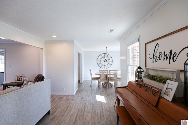 interior space with wood finished floors, visible vents, baseboards, ornamental molding, and a textured ceiling