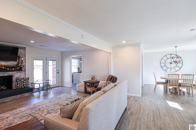 living area with visible vents, a brick fireplace, baseboards, and wood finished floors