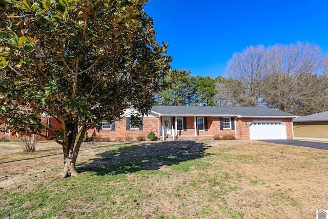 ranch-style home featuring aphalt driveway, an attached garage, brick siding, and a front yard