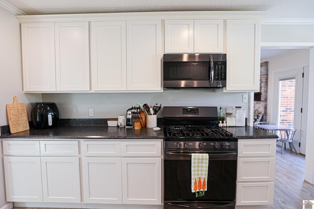 kitchen featuring stainless steel microwave, black range with gas stovetop, ornamental molding, and white cabinets