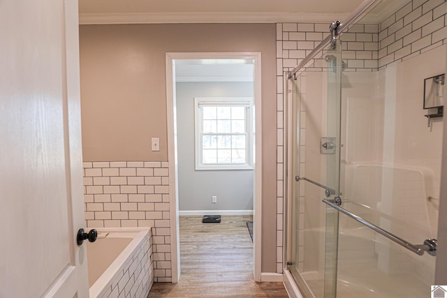 bathroom featuring wood finished floors, tiled tub, ornamental molding, a shower stall, and tile walls