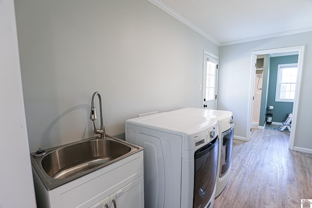 laundry area featuring light wood finished floors, laundry area, ornamental molding, a sink, and washer and dryer