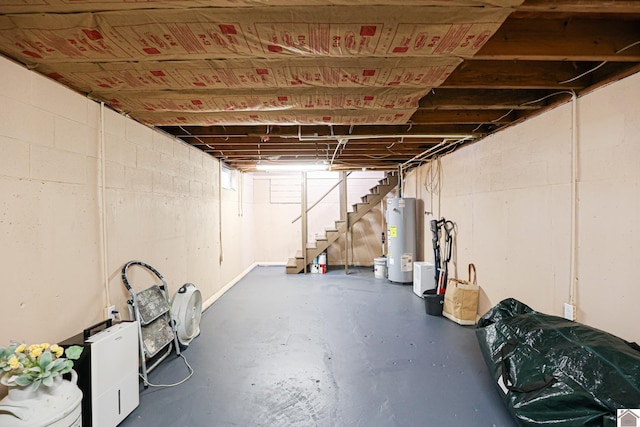 basement with stairway, concrete block wall, and water heater