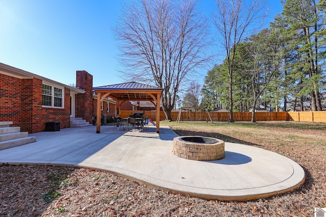 view of patio with entry steps, a gazebo, fence, and an outdoor fire pit