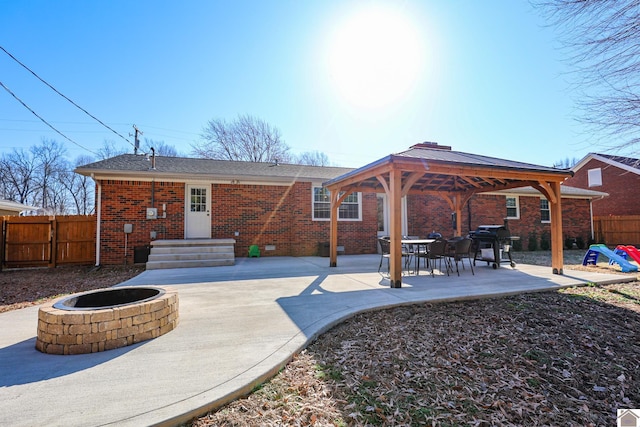 rear view of house with a patio, fence, a gazebo, a fire pit, and brick siding