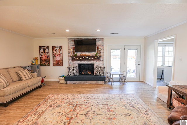 living area with visible vents, wood finished floors, crown molding, baseboards, and a brick fireplace