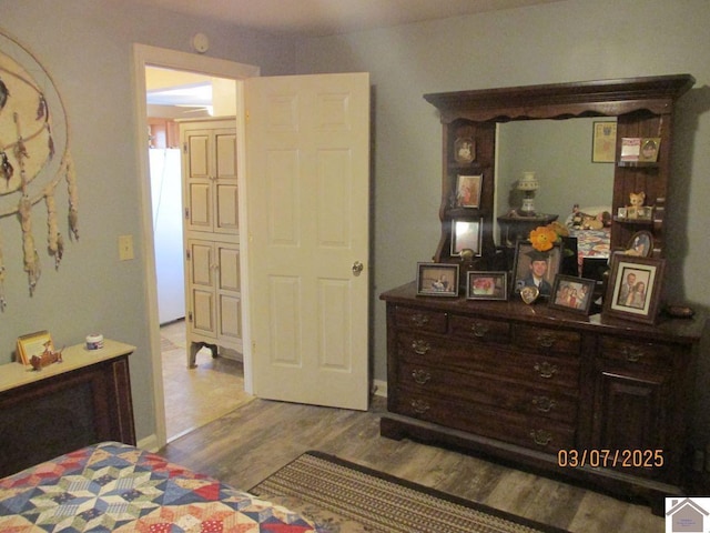 bedroom with wood finished floors and freestanding refrigerator