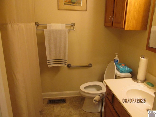 bathroom with vanity, toilet, baseboards, and visible vents