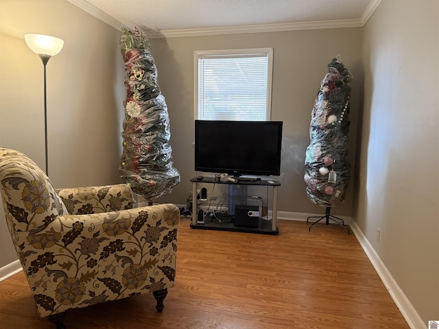 sitting room featuring ornamental molding, baseboards, and wood finished floors