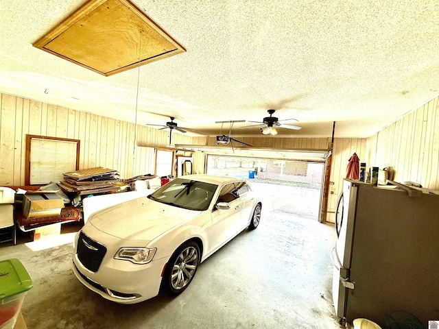 garage with wooden walls, a garage door opener, and freestanding refrigerator