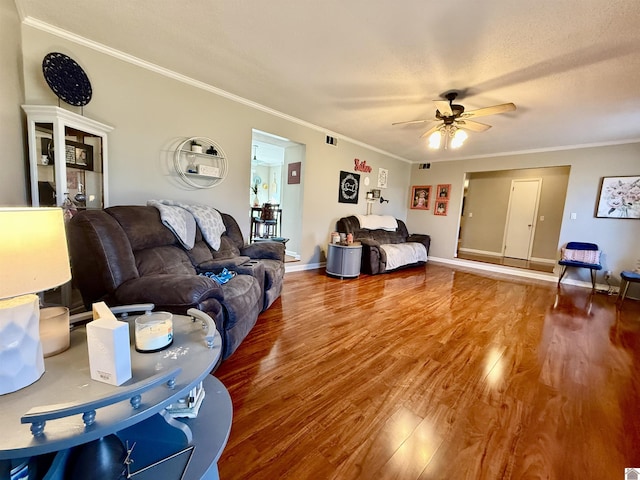 living area with a ceiling fan, wood finished floors, crown molding, and a textured ceiling