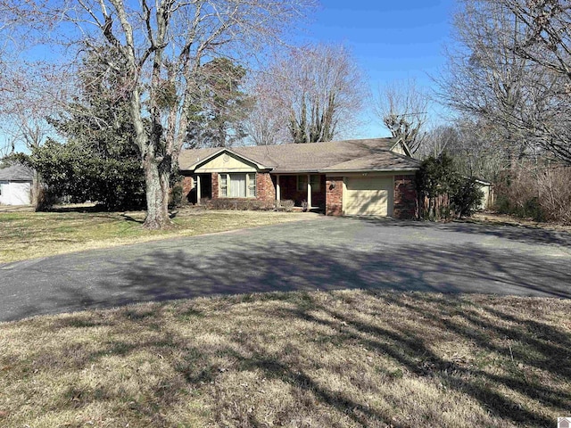 single story home with driveway, a front yard, brick siding, and an attached garage