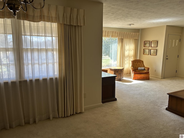 unfurnished room featuring baseboards, a textured ceiling, an inviting chandelier, and carpet flooring