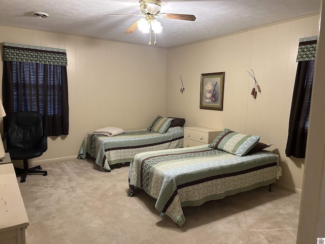 bedroom featuring a ceiling fan, light colored carpet, and a textured ceiling