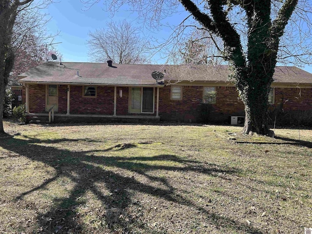 rear view of property with brick siding and a lawn