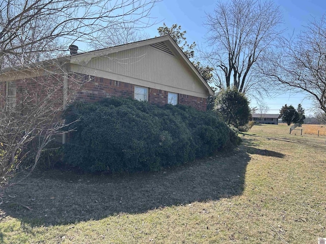 view of side of home with brick siding and a lawn