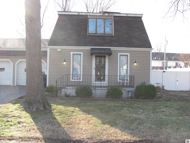 view of front of property featuring driveway, fence, roof with shingles, a front yard, and a garage