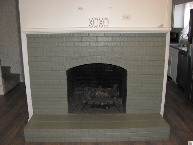 room details with dishwashing machine, wood finished floors, and a fireplace