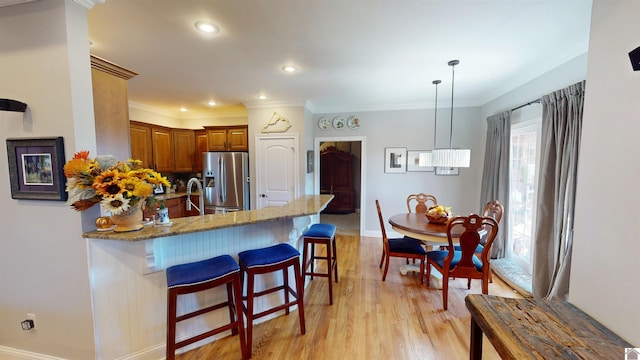 kitchen featuring light stone counters, brown cabinetry, light wood finished floors, a peninsula, and stainless steel fridge with ice dispenser