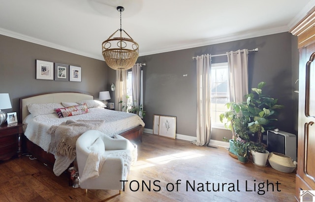 bedroom with a notable chandelier, wood finished floors, baseboards, and ornamental molding